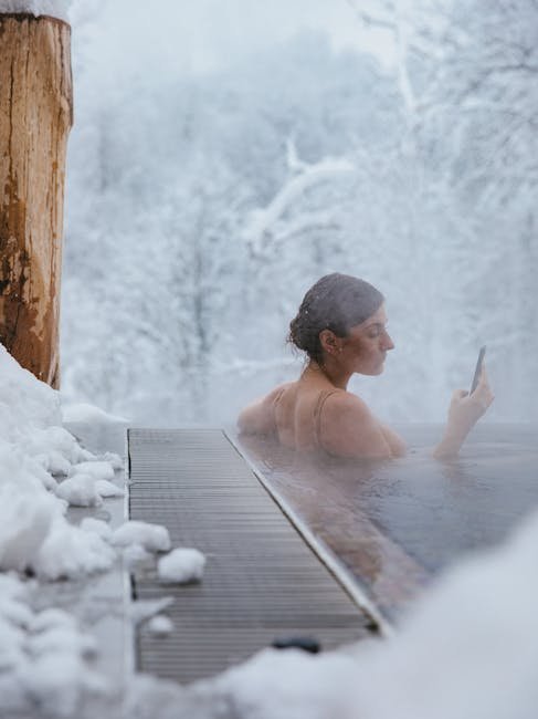 A woman relaxes in a steamy outdoor jacuzzi during winter, using her cellphone.