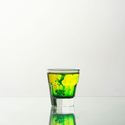 A captivating shot of a vibrant green liquid swirling in a glass, reflecting on a smooth surface.