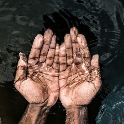 From above of crop anonymous male washing hands in clean water of lake in daytime